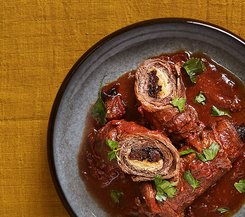 Gefüllte Rinderrouladen in Tomatensauce Ein Teller mit gefüllten Rinderrouladen in reichhaltiger Tomatensauce, garniert mit frischen Kräutern.