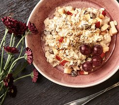 Bircher Müsli Schüssel mit Bircher Müsli, garniert mit frischen Apfelstücken, Rosinen und roten Trauben.