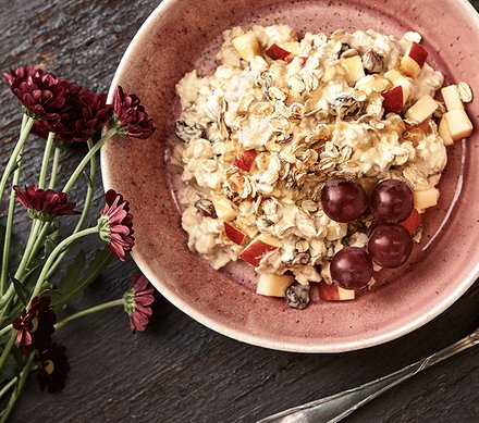 Bircher Müsli Schüssel mit Bircher Müsli, garniert mit frischen Apfelstücken, Rosinen und roten Trauben.