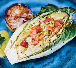 Gegrilltes Salatherz mit Tomaten und Dressing Gegrilltes Salatherz mit Tomaten und Dressing auf einem blauen Teller