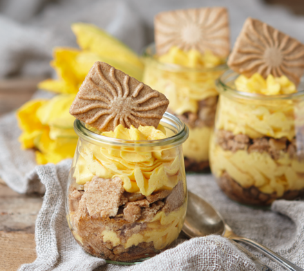 Schichtdessert mit Keksen und Creme Gläser mit Schichtdessert aus zerbröselten Keksen und gelber Creme, dekoriert mit einem Keks.