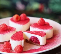 Himbeerherzen Kleine Himbeer-Käsekuchen auf einem Teller, dekoriert mit frischen Himbeeren.