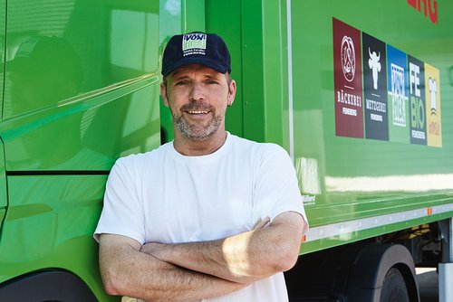 LKW-Fahrer vor einem grünen Feneberg-LKW