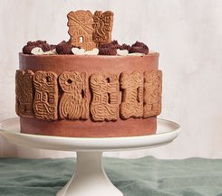 Spekulatiustorte mit Schokoladencreme Eine Spekulatiustorte, verziert mit Spekulatius-Keksen und Schokoladencreme-Tupfen, auf einer weißen Tortenplatte.