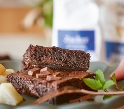 Saftige Schokoladen-Brownies Ein Teller mit zwei Stücken saftiger Schokoladen-Brownies, garniert mit Schokoladenstückchen und Minzblättern.