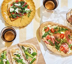 Brätscher Verschiedene belegte Flammkuchen auf einem gedeckten Tisch, serviert mit Getränken in Gläsern.