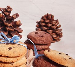 Schokoladenkekse Schokoladenkekse mit Schleife und Tannenzapfen im Hintergrund