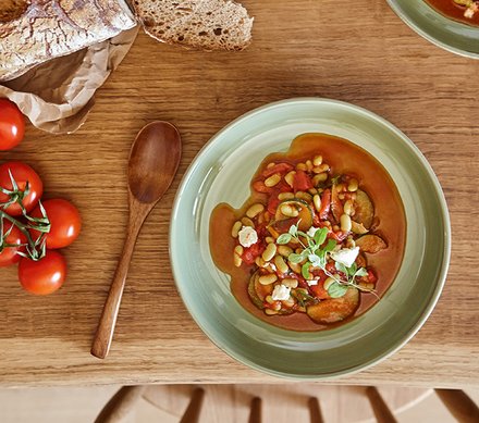 Gemüseeintopf mit Tomaten und Brot Gemüseeintopf mit Tomaten und Brot auf einem Holztisch