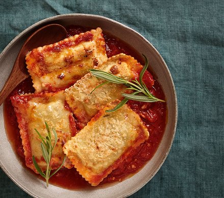 Ofenmaultaschen in Tomatensauce Ein Teller mit Ofenmaultaschen in Tomatensauce, garniert mit frischen Kräutern.