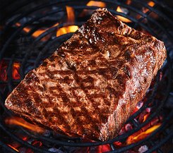 Steak auf Grill über offenem Feuer Ein großes Stück Steak auf einem Grill über offenem Feuer