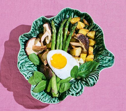 Gebratenes Gemüse mit Spargel und Spiegelei Ein Teller mit gebratenem Gemüse, Pilzen, Spargel und einem Spiegelei, angerichtet auf einem grünen, blattförmigen Teller.