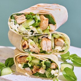 Gesunde Wraps mit gegrilltem Hähnchen und Feta Drei gesunde Wraps gefüllt mit gegrilltem Hähnchen, frischen Gurken, Salat und Feta-Käse, auf einem weißen Untergrund präsentiert.