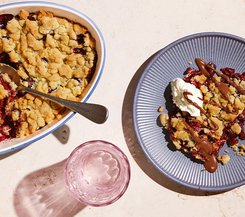 Zwetschgen-Zimt-Crumble Zwetschgen-Zimt-Crumble in einer ovalen Auflaufform, eine Portion auf einem Teller mit Schlagsahne und Schokoladensoße.