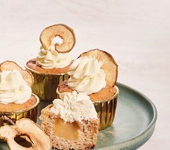 Apfelcupcakes mit Sahne und Apfelmusfüllung Drei Apfelcupcakes mit Sahnehaube und getrockneten Apfelscheiben, einer davon angeschnitten und gefüllt mit Apfelmus